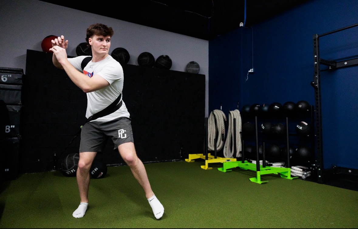 Baseball player doing a resistance band rotational throw drill on the turf at Pinnacle