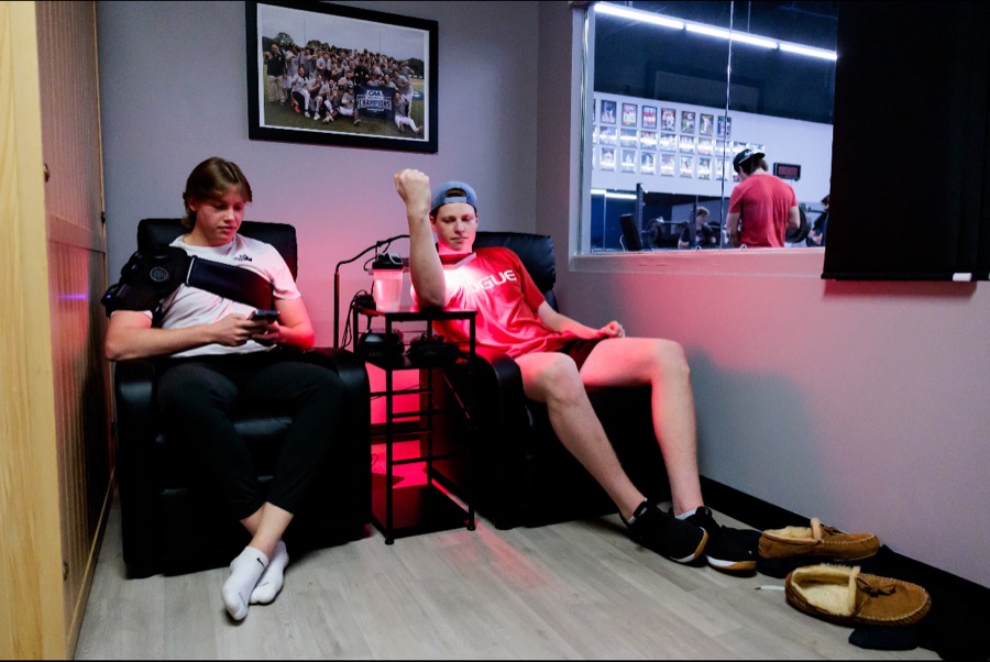 Two baseball players recovering at Pinnacle, one in a shoulder compression wrap and one under red light therapy