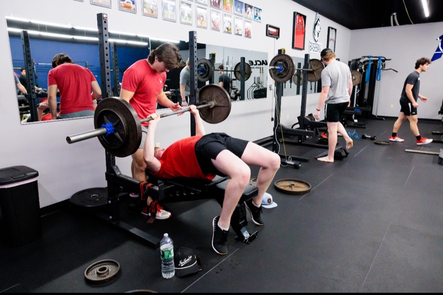 Baseball player bench pressing with a teammate spotting in the Pinnacle weight room