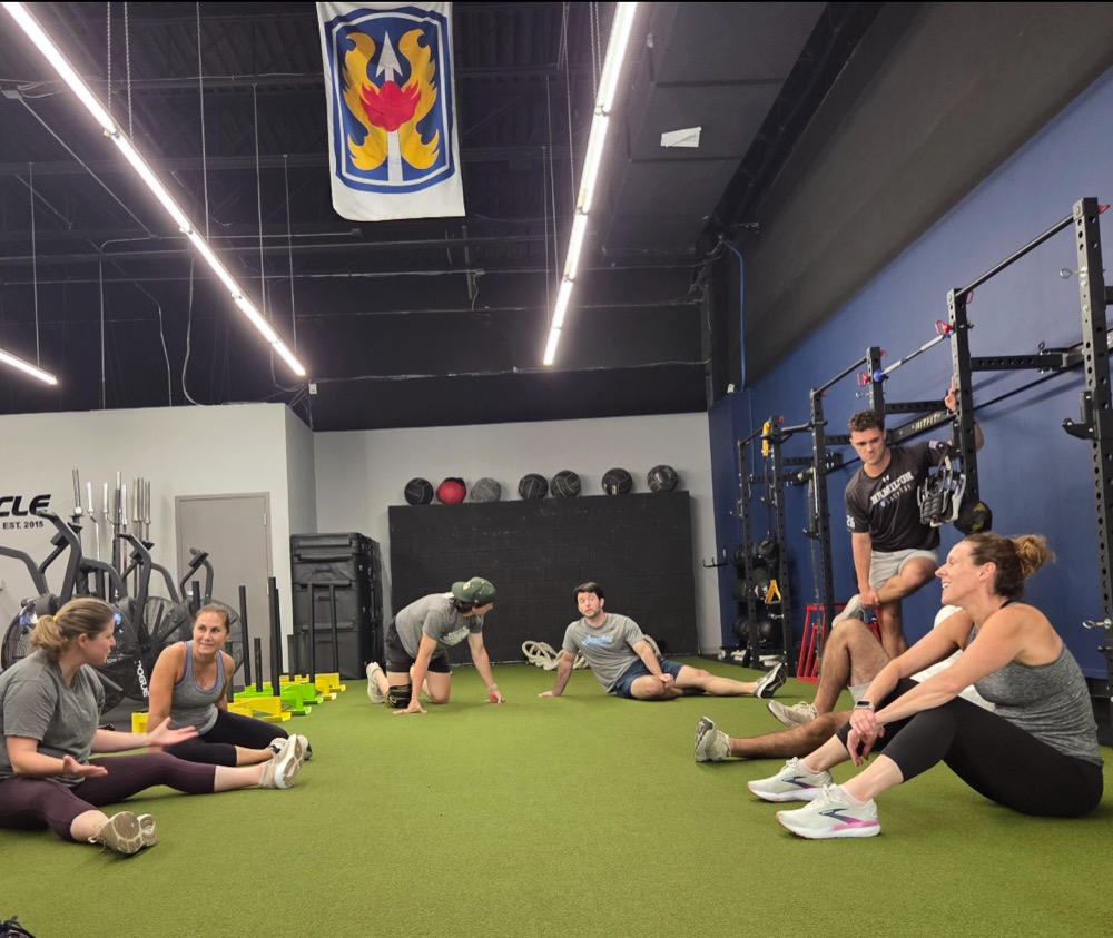 Adult class members stretching together on the turf at Pinnacle