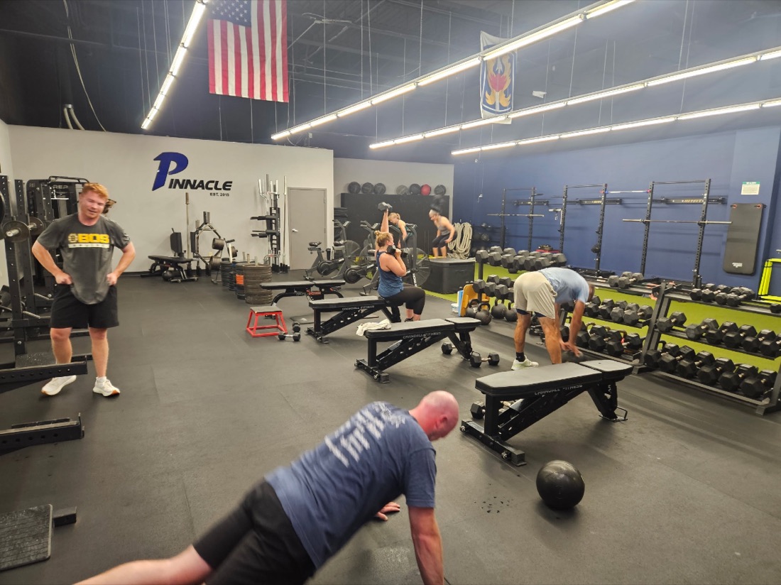 Pinnacle members working out across the gym floor under the Pinnacle wall logo