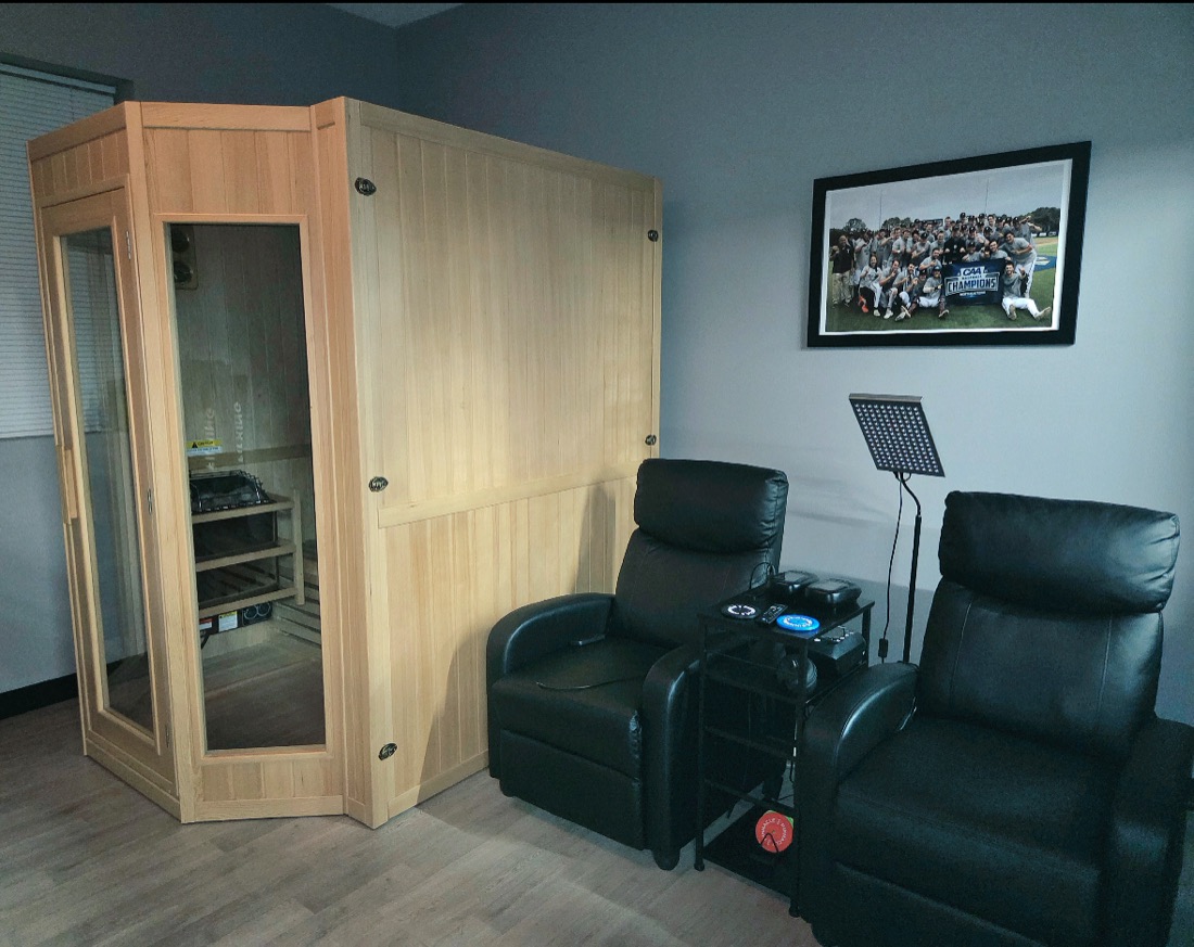 Pinnacle's recovery room with a wooden sauna, two recliners and a red light therapy panel